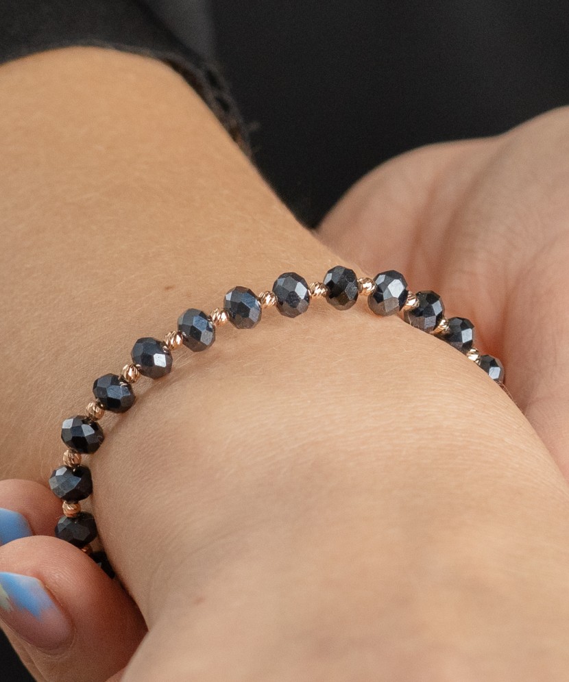 Mustast lõngast käevõru kulla ja oonüksitega