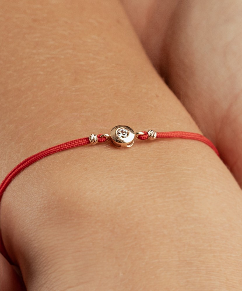 Punasest lõngast käevõru kulla tsirkoonist ripatsiga